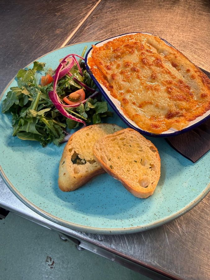 Baked lasagne with garlic bread and dressed leaves